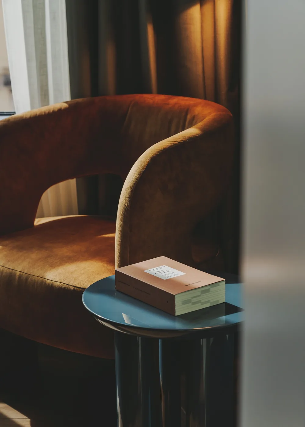 Butaca junto a una mesa auxiliar con un libro, a la luz de la tarde